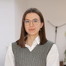 Eine freundliche Bestatterin von Vogt & Kamp Bestattungen Düsseldorf lächelt im stilvollen, dezent beleuchteten Innenraum.