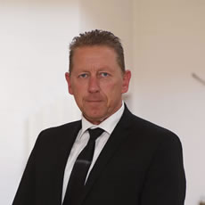 Bestatter Düsseldorf in schwarzem Anzug vor hellem Hintergrund - professionell und seriös für Bestattung Düsseldorf.